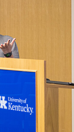 UK doctoral graduate Rebecca Ferrell beside a podium speaking at a symposium for women leaders in arts administration