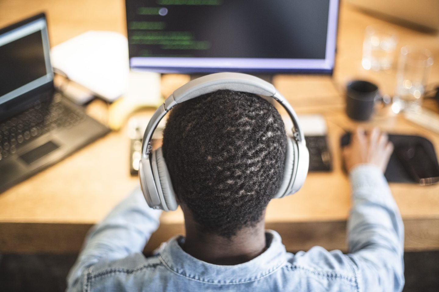 Rear view of male hacker working on computer at office