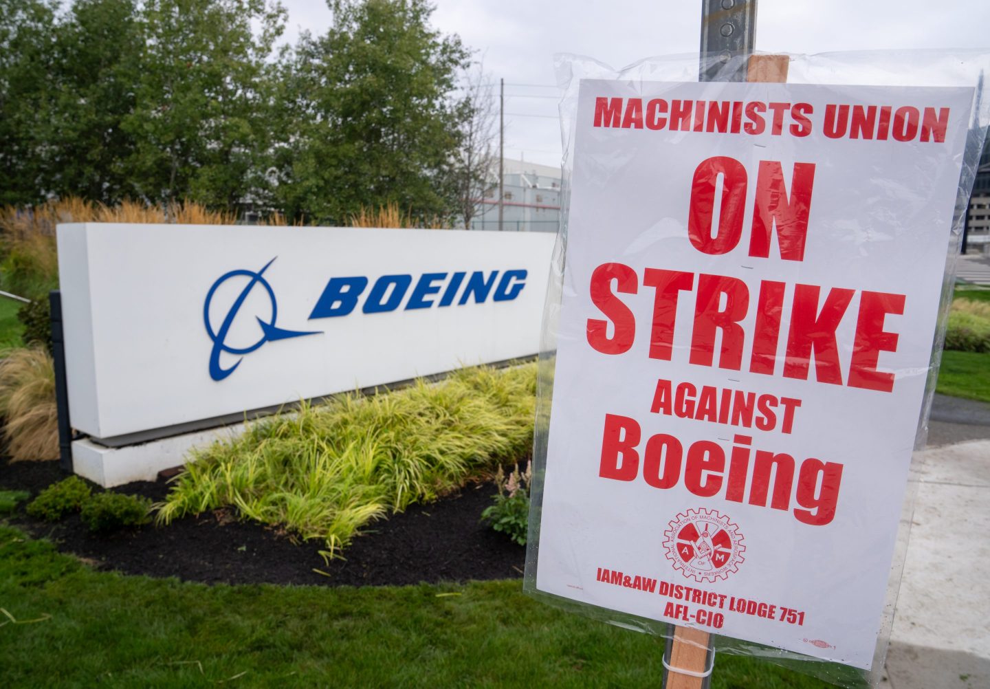 A striking Boeing worker's sign is seen in front of a Boeing sign at a factory in Seattle.