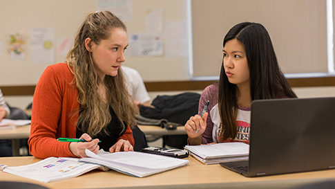 two female students working at a desk.
