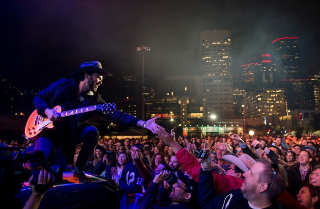 Band plays in a dark area with city of Austin lights as the backdrop