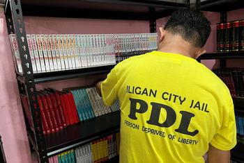 A prisoner arranges books in the library at Iligan City Jail.