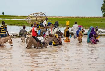 Residents of Rann, in north-east Nigeria, wade through the flooded main road, which is now inaccessible by vehicle.