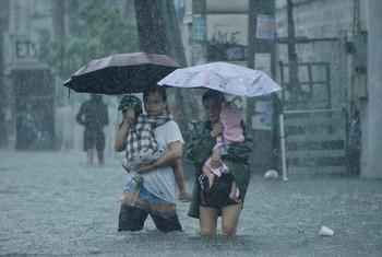 Parents carry their children as they walk on a flooded street in Quezon City, Philippines.