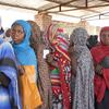 Women wait in line to receive cash distributions in Sudan.