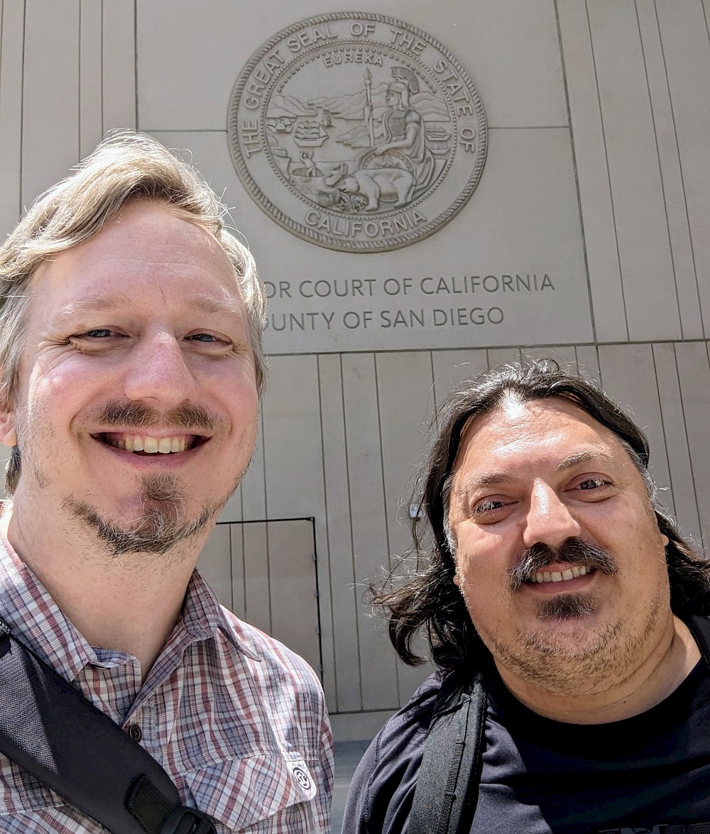 myself on the left in a pink, check pattern shirt, Al on the right in a black shirt, in front of the courthouse