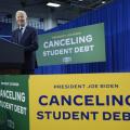 Joe Biden giving a speech in front of 'Canceling Student Debt' signs