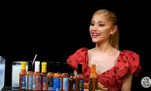 A woman sits in front of a table covered with hot sauce.