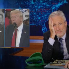 A man in a suit sits behind a talk show desk. Two side-by-side images of Donald Trump are visible in the top left.