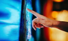 Close up of woman's hand touching illuminated and multi-coloured LED display screen