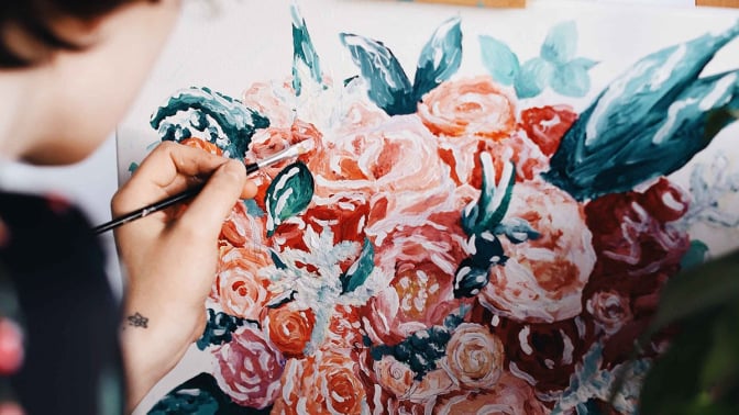 Person painting flowers on canvas