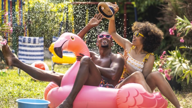 Man and woman relax and laugh in an inflatable flamingo pool