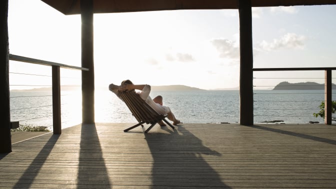 a person sits on a deck outstretched on a chair with the sun shining