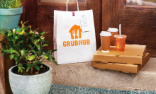 a grubhub bag on a bench with delivery boxes and drinks