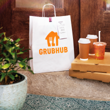 a grubhub bag on a bench with delivery boxes and drinks