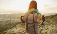 woman with backpack looks at the sunset