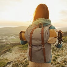 woman with backpack looks at the sunset