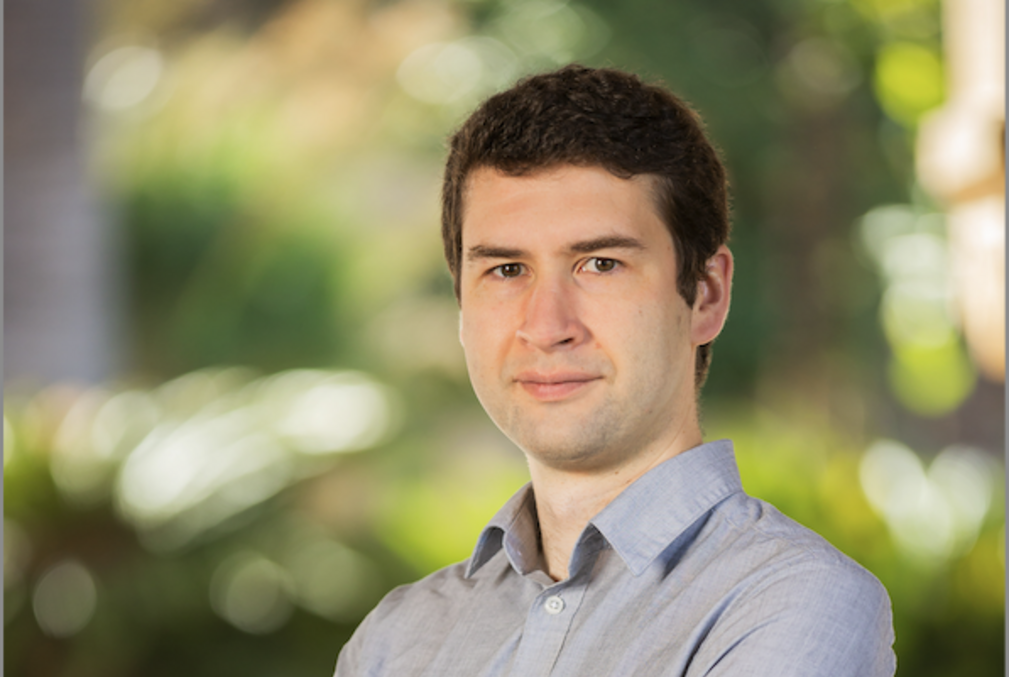 Steven Banik wearing a gray collared shirt and standing in Stanford's Main Quad