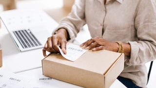 Eine Person klebt ein Rücksendeetikett auf ein Paket.