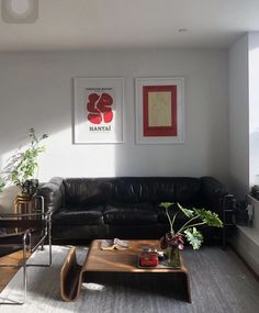 a living room with black leather couches and two pictures on the wall above them