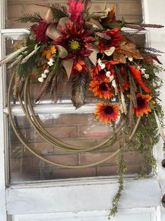 a wreath is hanging on the front door with flowers and foliage around it, as well as other decorations