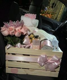 a wooden crate filled with pink roses and other items in the back of a car