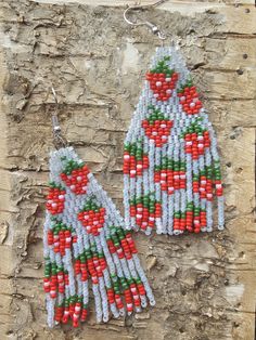 the beaded earrings are made from red and white beads with green leaves on them