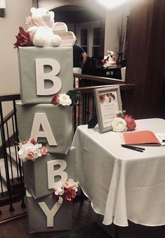 a baby shower cake on top of a white tablecloth covered table with flowers and cards