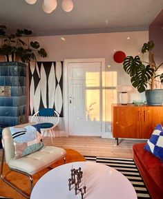 a living room filled with lots of furniture next to a white table and wall mounted plant