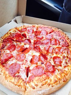 a pepperoni pizza sitting in a box on top of a table