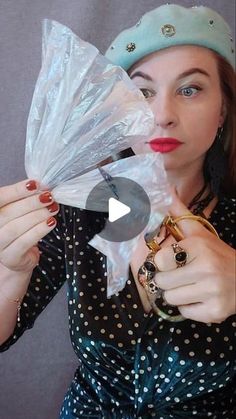 a woman is holding some plastic bags in her hands and wearing a hat with pearls on it