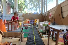 a child is sitting at a table with toys on the floor and in front of him