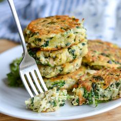 a stack of food on a white plate with a fork in the middle and broccoli florets next to it