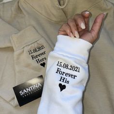 a person holding onto a white shirt with black writing on it and a name tag attached to the sleeves