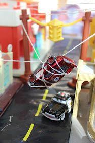 a toy car is being pulled by a tow truck on a track in the city