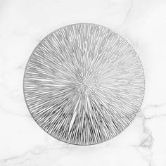 a white marble table topped with a metal plate filled with lots of silver colored lines