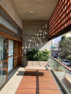 a wooden bench sitting on the side of a building next to a tall glass window