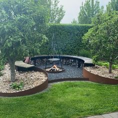 an outdoor fire pit surrounded by grass and trees