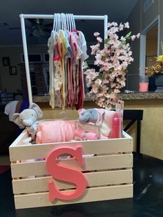 a wooden crate with clothes and stuffed animals in it, sitting on a black table