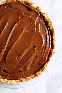 a pie with chocolate frosting on top sitting on a table