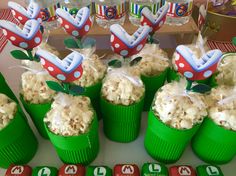 some green cups filled with popcorn sitting on top of a table next to other cupcakes