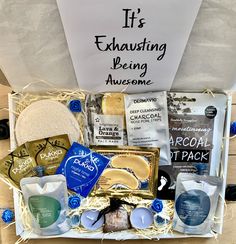 an open gift box filled with personal care items on a wooden table next to a sign that says it's exhausting being awesome