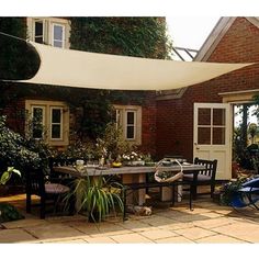 an outdoor table and chairs with a white awning over it's top in front of a brick building