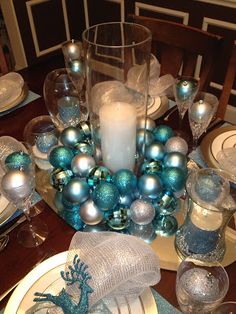 a dining room table set for christmas with blue and silver decorations