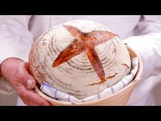 a person holding a loaf of bread with a star on it in their hand, while wearing a white coat