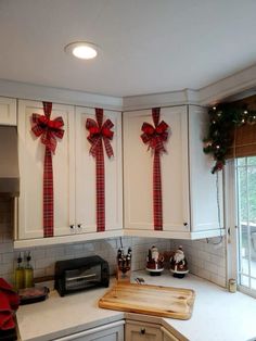 a kitchen decorated for christmas with bows on the cabinets