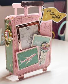 a pink suitcase with pictures and tags attached to the handle, sitting on a table