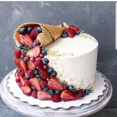 a cake decorated with strawberries, blueberries and raspberries