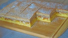 two slices of cake on a wooden cutting board with powdered sugar around the edges