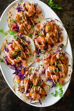 chicken tacos with cole slaw on a white plate next to cilantro